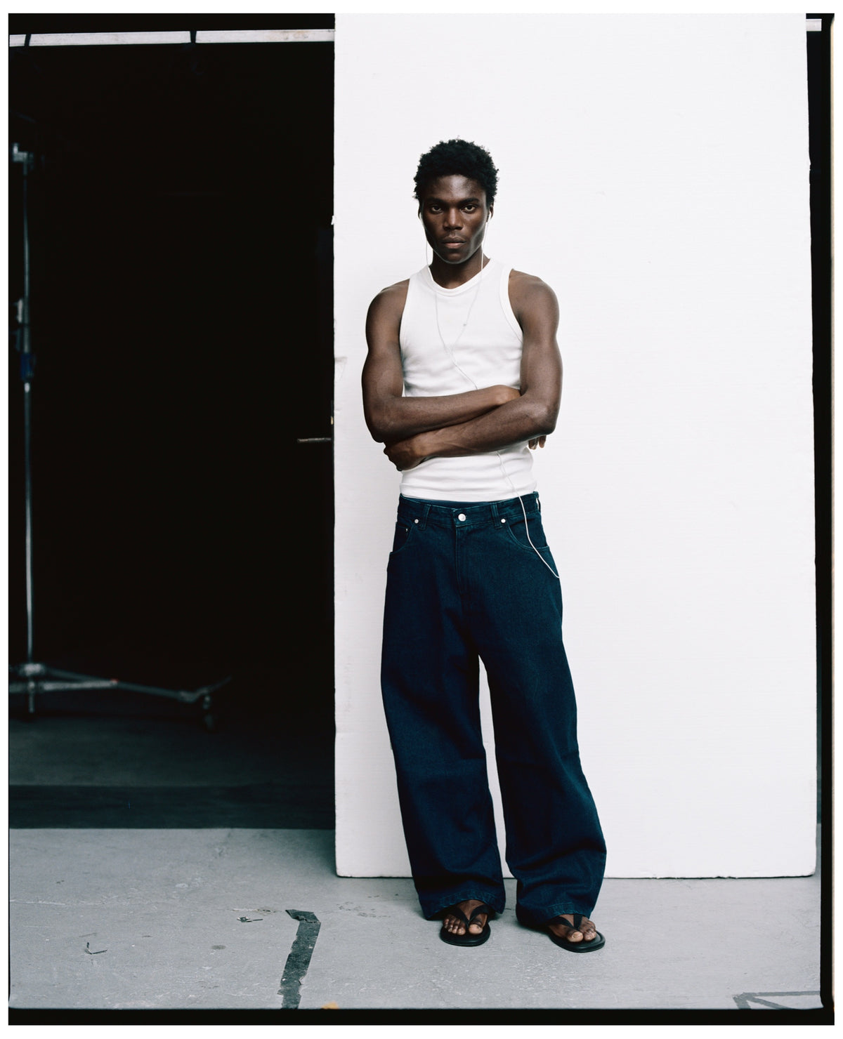 REAMO Denim lookbook – Sayeem raw denim with a white tank top, arms crossed