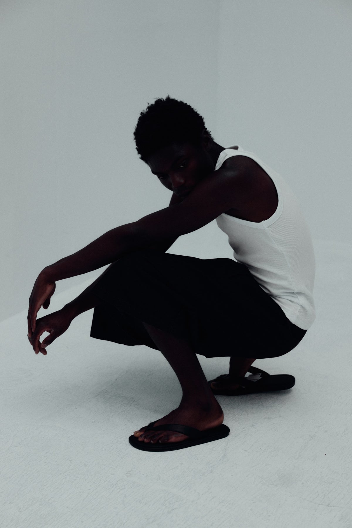 REAMO Denim lookbook – model crouching in denim shorts and a white tank top