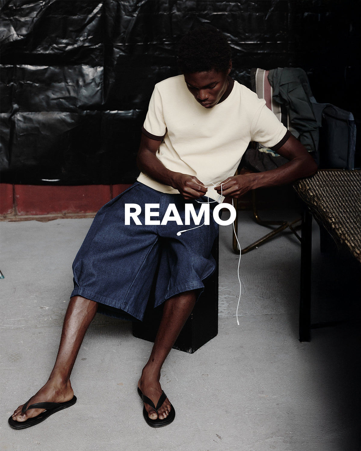REAMO Denim lookbook – seated in wide denim shorts and a cream T-shirt